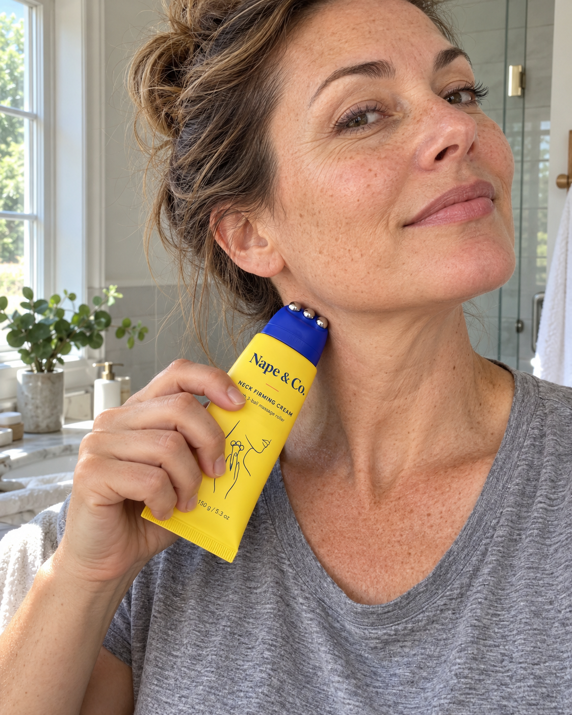 Woman rolling the Nape & Co. neck cream roller upward along her neck